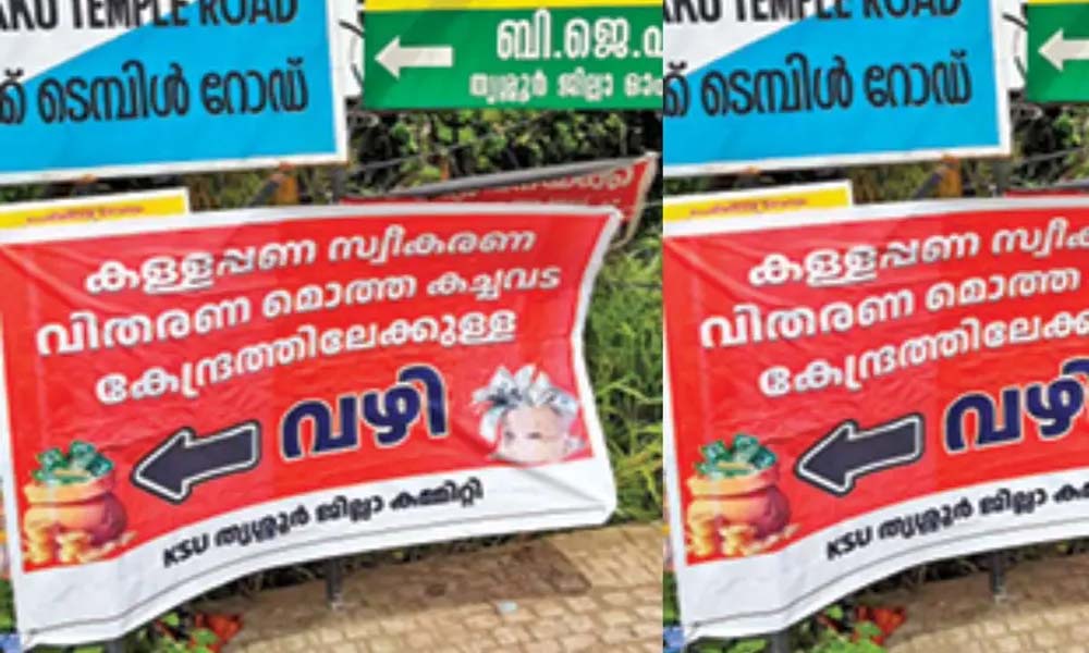 'കള്ളപ്പണ സ്വീകരണ വിതരണ മൊത്തക്കച്ചവട കേന്ദ്രത്തിലേക്കുള്ള വഴി'; BJP ഓഫീസിനു സമീപം ബാനര്, പ്രതിഷേധം